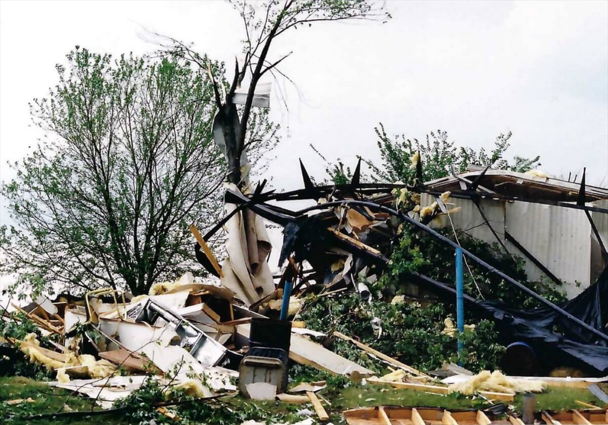 Storm-damaged building, trees, and scattered debris